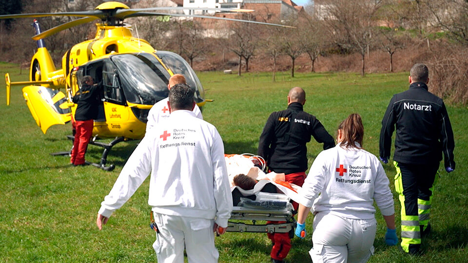Die Heli-Crew trägt Julian zum Hubschrauber.